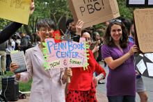 Chi-ming Yang and other marchers hold signs in support of Penn Book Center at rally on Locust Walk