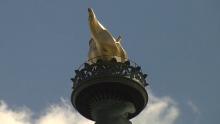 torch of Statue of Liberty in front of blue sky with white clouds