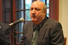 Professor Anthony DeCurtis, sitting, speaks into microphone in Kelly Writers House