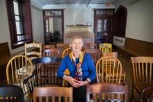 Deb Burnham, smiling, sits in row of chairs in Kelly Writers House