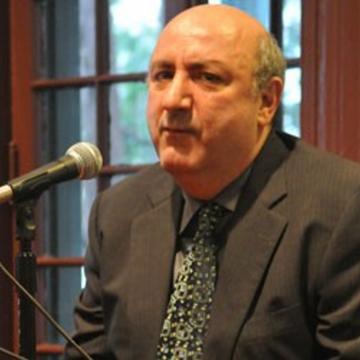 Professor Anthony DeCurtis, sitting, speaks into microphone in Kelly Writers House