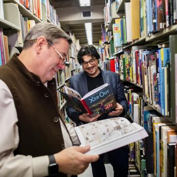 Adjunct Professor Robert Berry, left, and Assistant Professor of English Jean-Christophe Cloutier, who teach the undergraduate course Making Comics, enjoy two comics that are part of Van Pelt-Dietrich's collection, available to students, faculty, and staff.