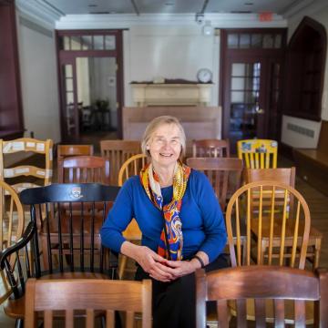 Deb Burnham, smiling, sits in row of chairs in Kelly Writers House