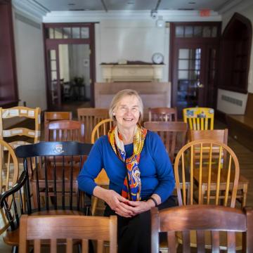 Deb Burnham, smiling, sits in row of chairs in Kelly Writers House