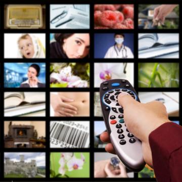 hand holding remote in front of a screen subdivided into a 6x6 grid of varied, colorful images (such as a close-up of a rose, a woman speaking on a headset, and a fireplace) separated by black borders 