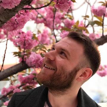 Portrait of Jacob Myers looking up at pink flowers in a tree